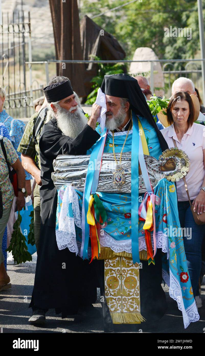 A Greek Orthodox priest carrying a silver icon of the Virgin Mary ...