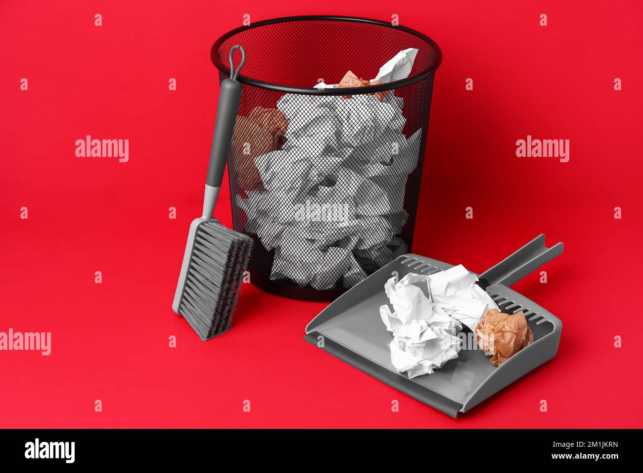 Office rubbish bin with crumpled paper, scoop and brush on color background Stock Photo