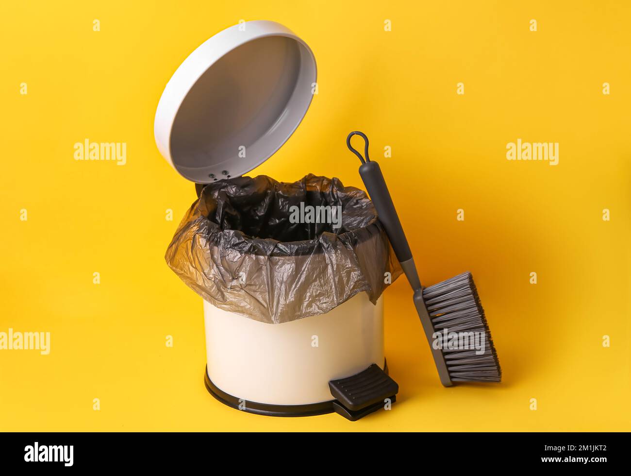 Open rubbish bin and brush on yellow background Stock Photo