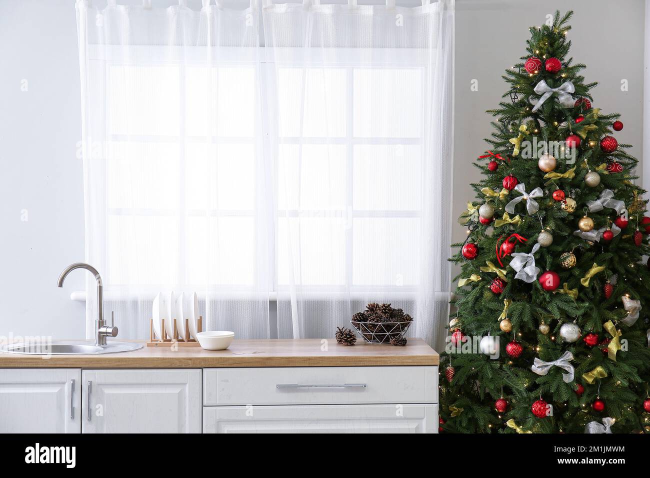 Interior of kitchen with Christmas tree, white counters and window