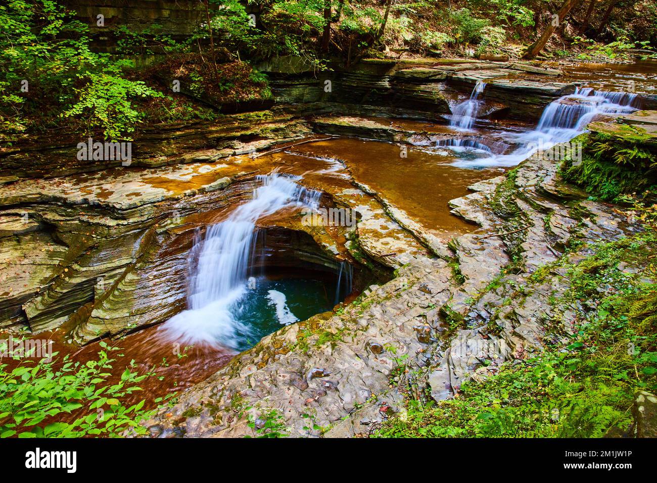 Gorge with two tiers of waterfalls flowing through forest in Upstate ...