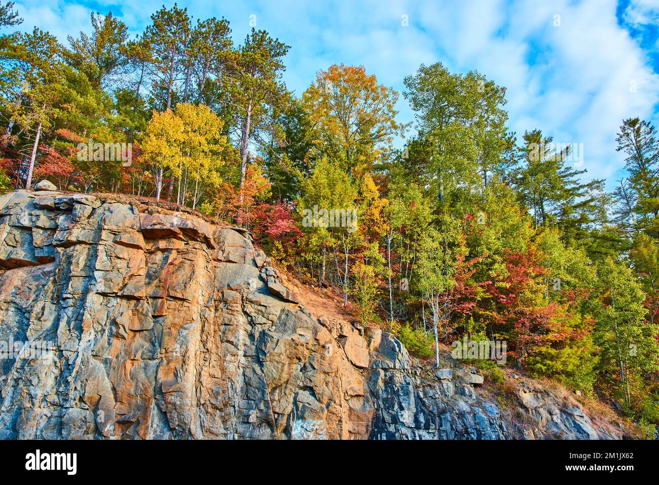 Cliff edge with rows of colorful fall leaves on top Stock Photo