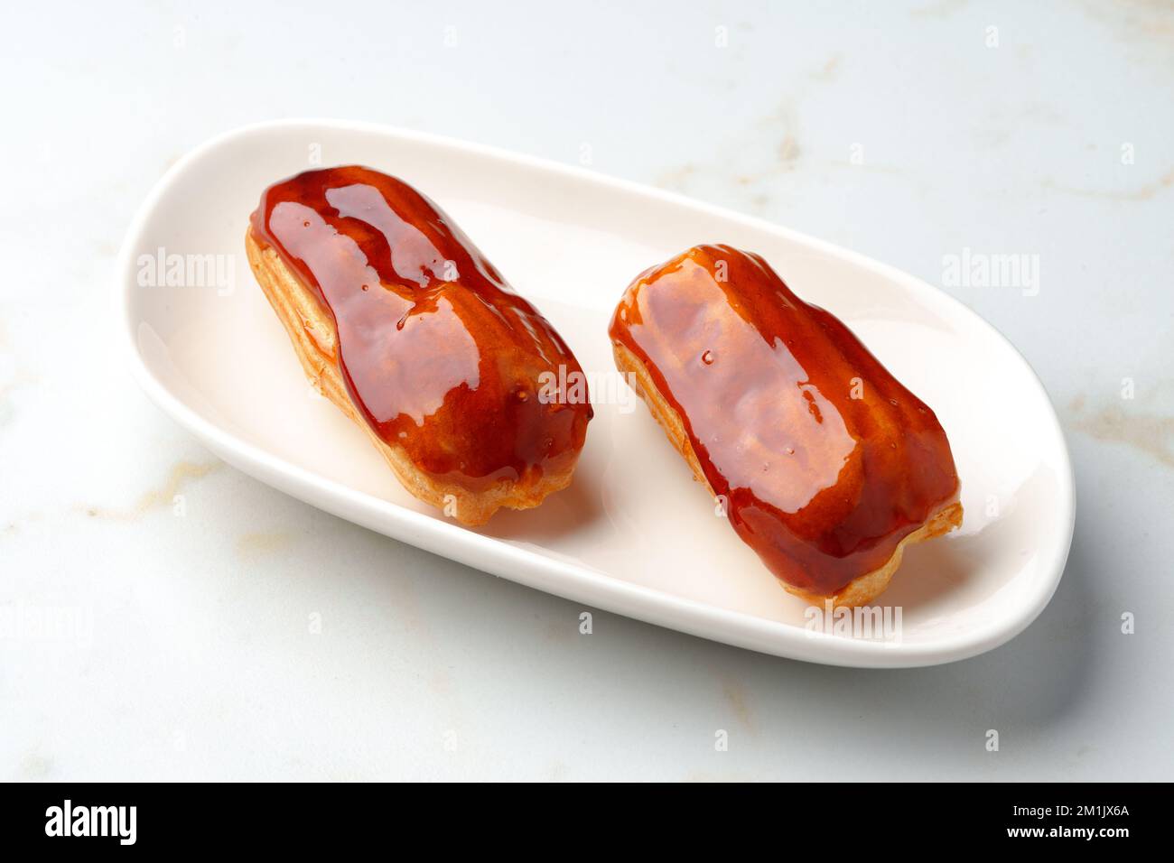 Two caramel eclairs on a white plate Stock Photo