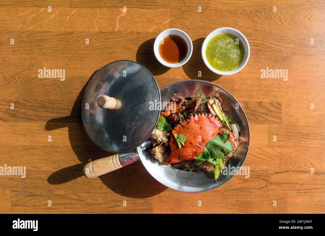XO pot crab with vermicelli, a restaurant-quality seafood noodle dish served on wooden table with fish sauce and spicy sauce. Top View Stock Photo