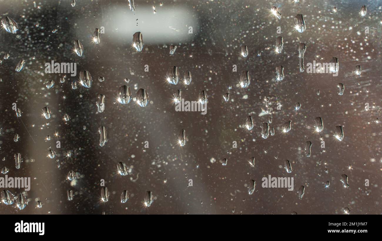Raindrops fall on the window close-up. Rain, rainy, depressive, dreary weather. Wet drop water. Splashes of water with large drops on the glass. On wi Stock Photo