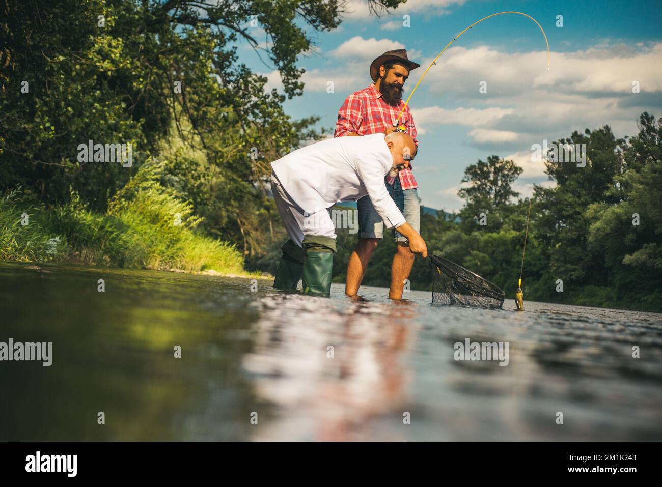 Two men friends fisherman fishing on river. Old father and son with rod ...
