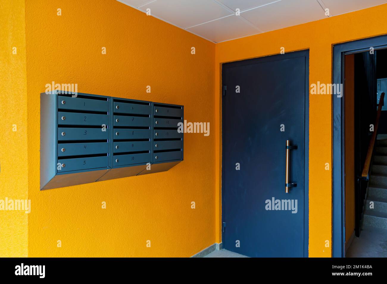Gray mailboxes on an orange wall in the entrance of an apartment building Stock Photo