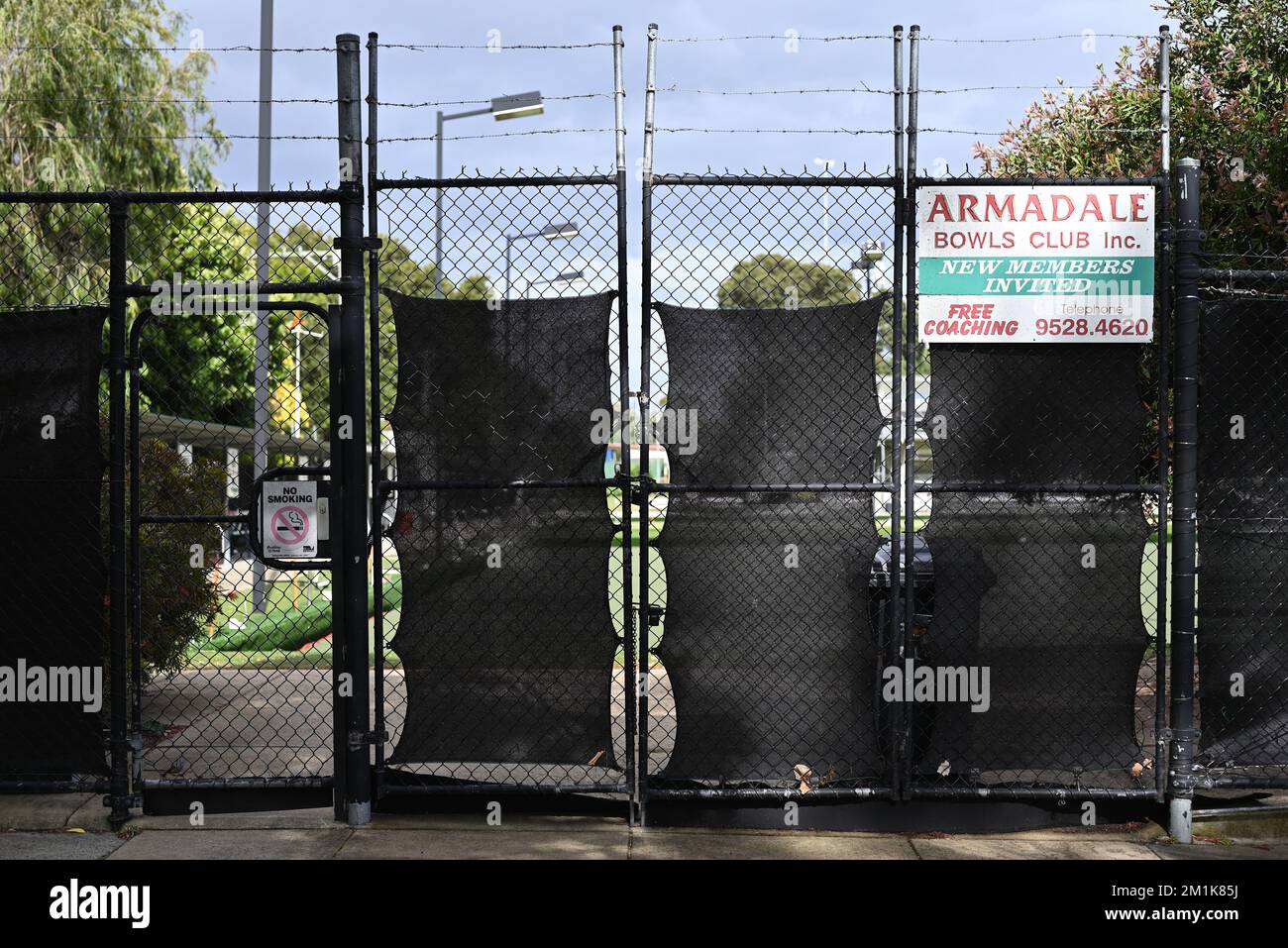 Western entrance to the Armadale Bowls Club, on Nelson St, featuring signs, black fencing, and barbed wire Stock Photo