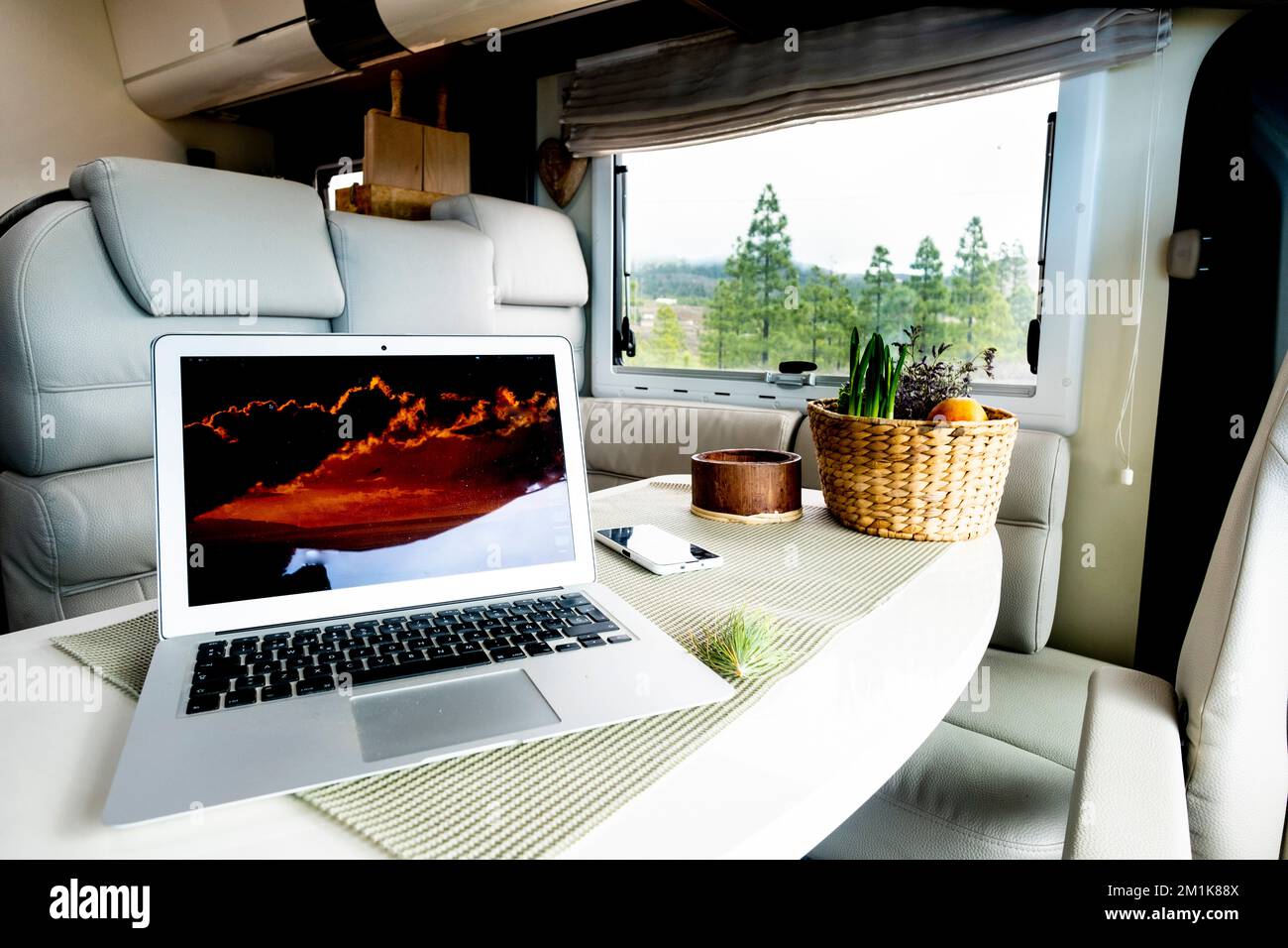 Alternative office and workstation for freedom smart working or digital nomad lifestyle concept. Laptop computer on a motor home table with nature and Stock Photo