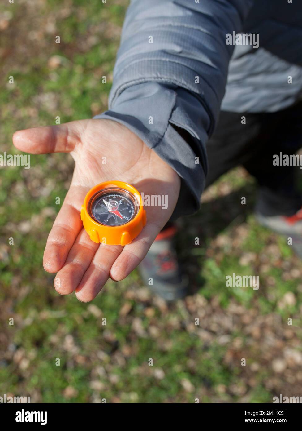Child boy holding toy compass on hand. Orientation games in nature for children Stock Photo