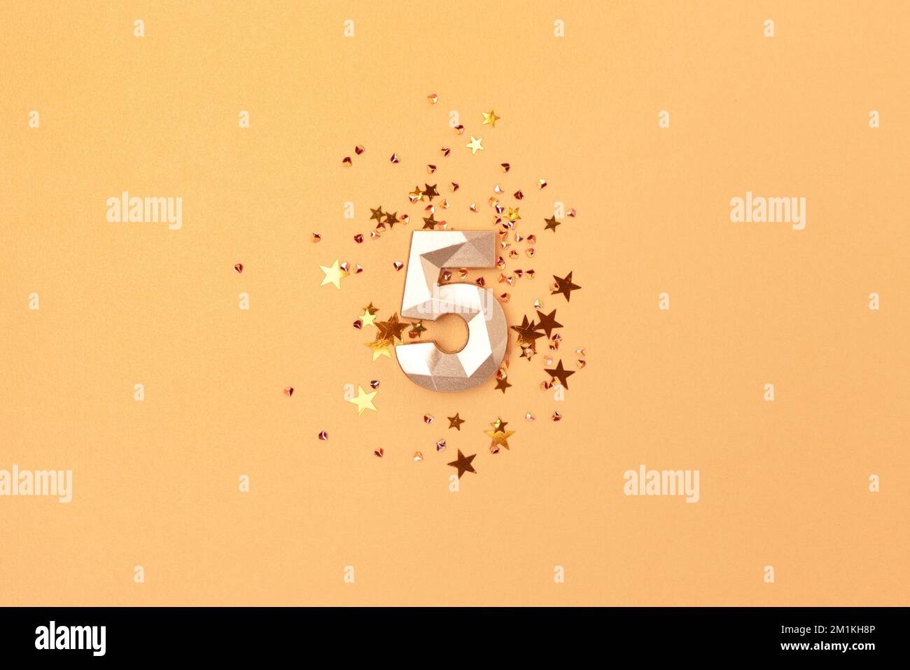 Gold colored number 5 and stars confetti. Festive monochrome concept. Stock Photo