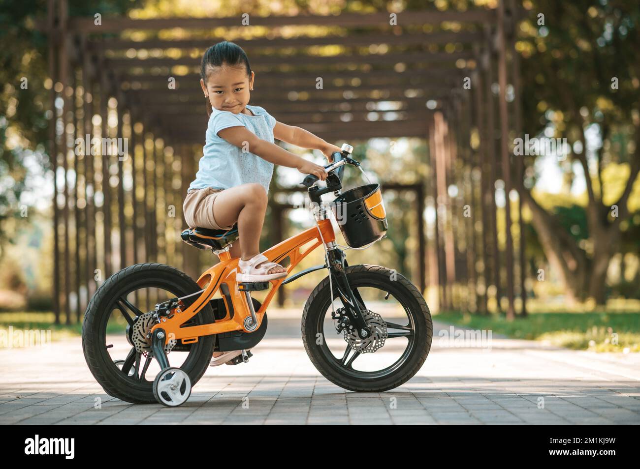 Happy little girl riding a bike and looking excited Stock Photo Alamy