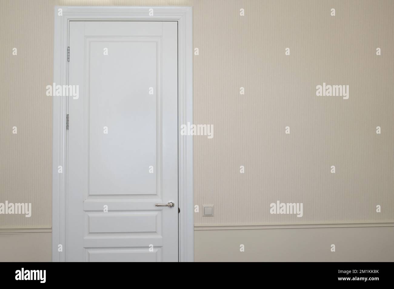 White door on a beige wall in an empty room. Details in the interior
