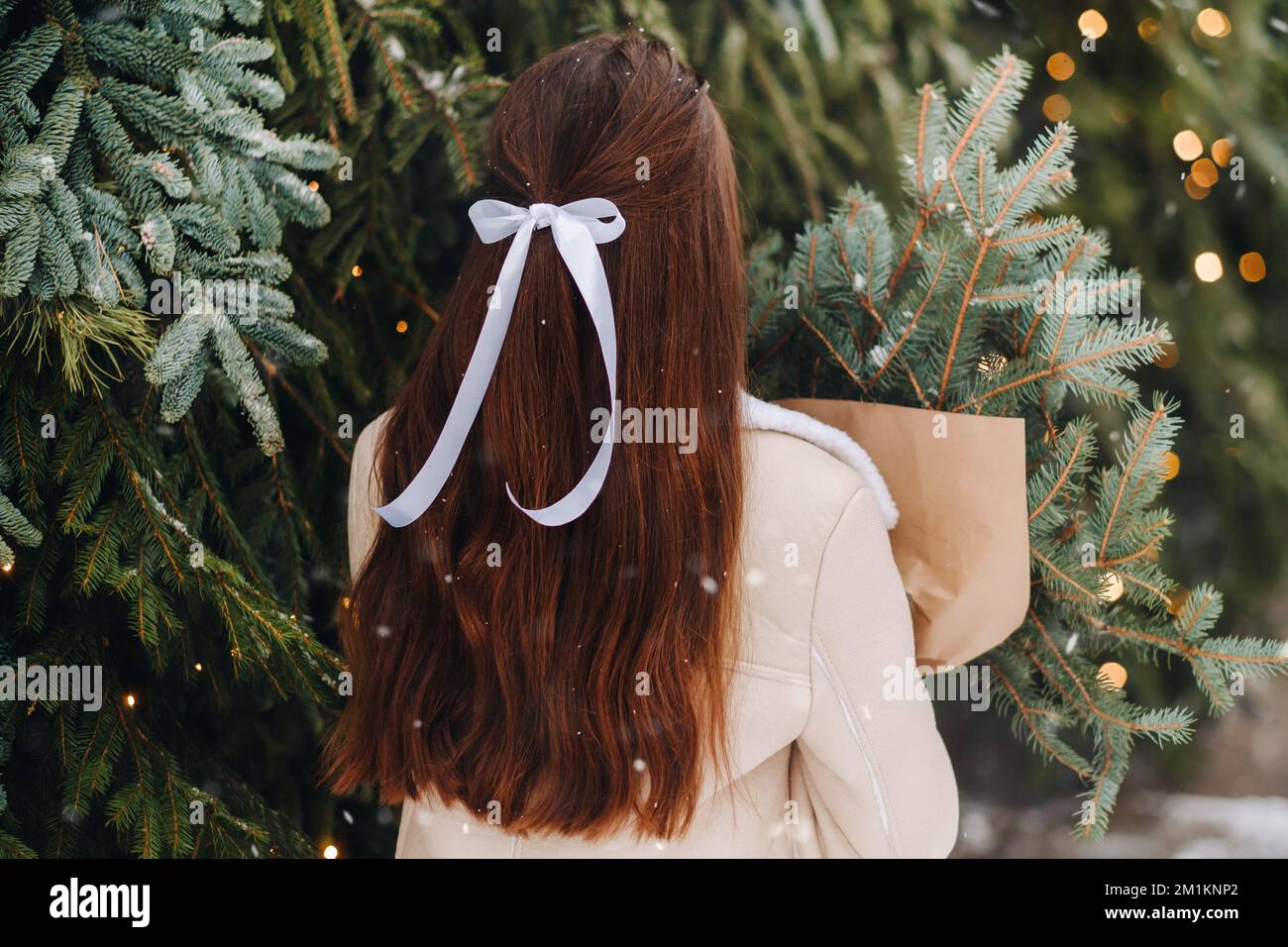 A girl with long hair stands with her back in a winter forest with a ...
