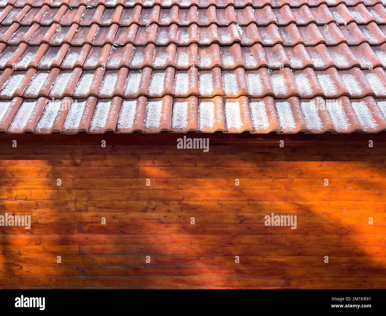 A wooden cabin with snow on the roof shingles Stock Photo