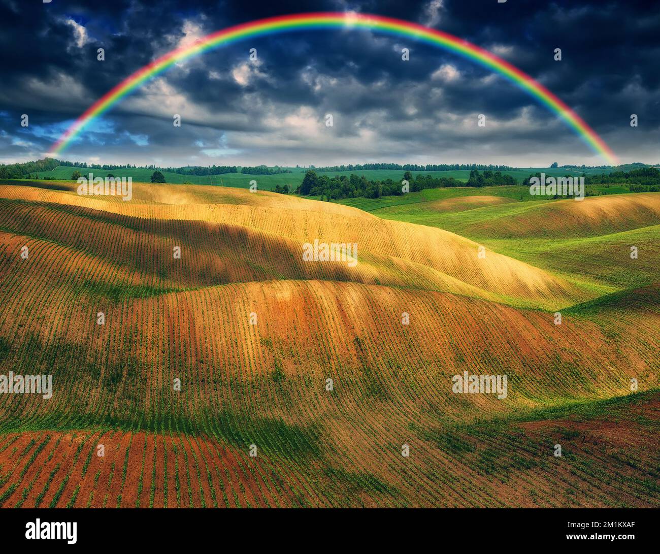 Rainbow and dramatic gray sky with clouds landscape. picturesque hilly ...