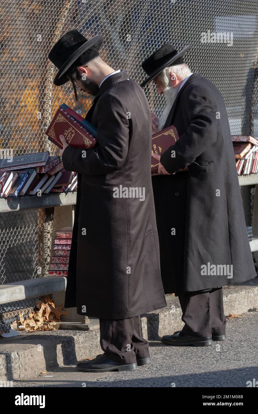 Two orthodox jewish men dressed in black shop for religious books at an