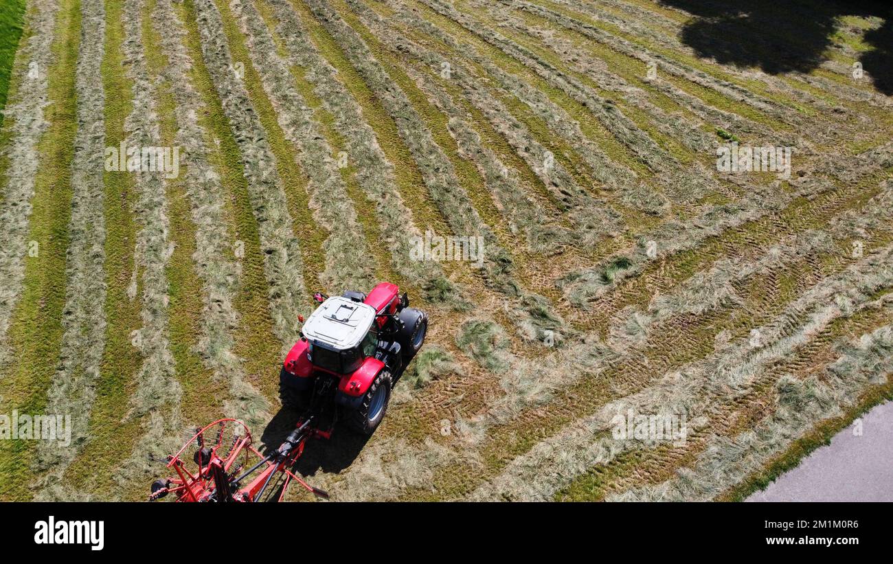 An aerial view of a tractor mounted with a rotary rakes moving through ...