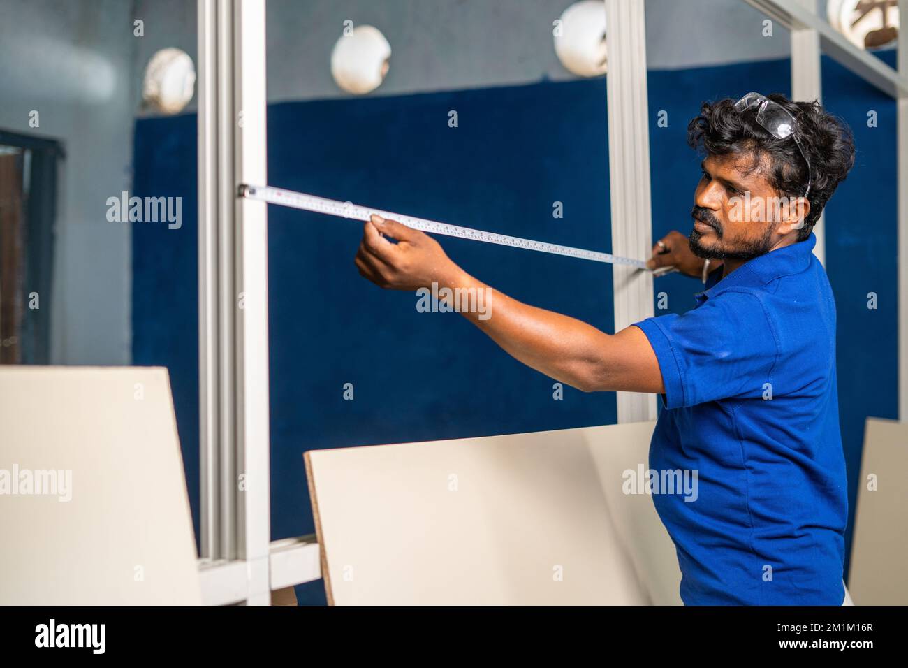 plumber busy working by measusing tape and fixing wood at workplace