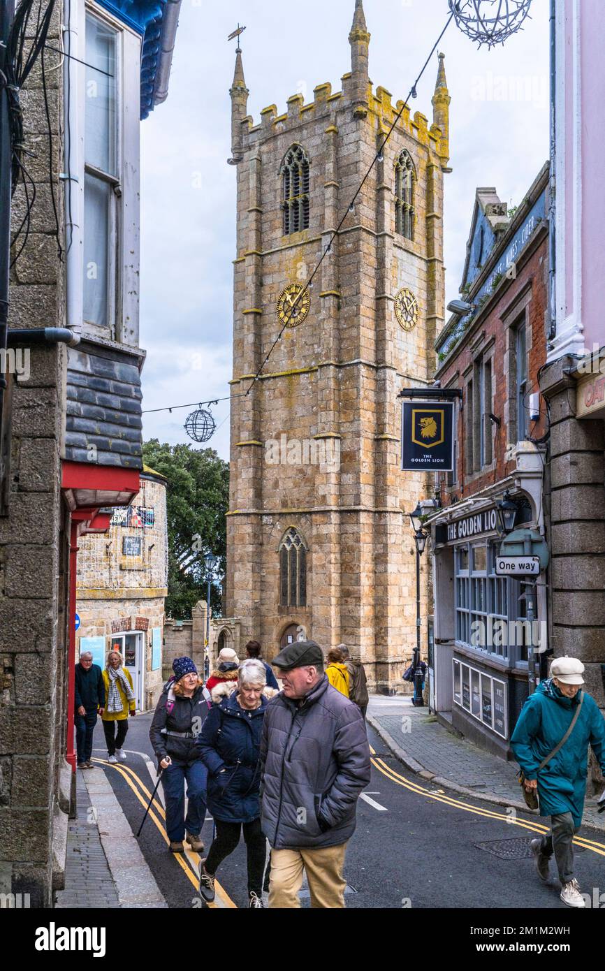 Visitors walking along St Andrews Street with St Eia Church in the background in the historic coastal town of St Ives in Cornwall in England in the UK Stock Photo