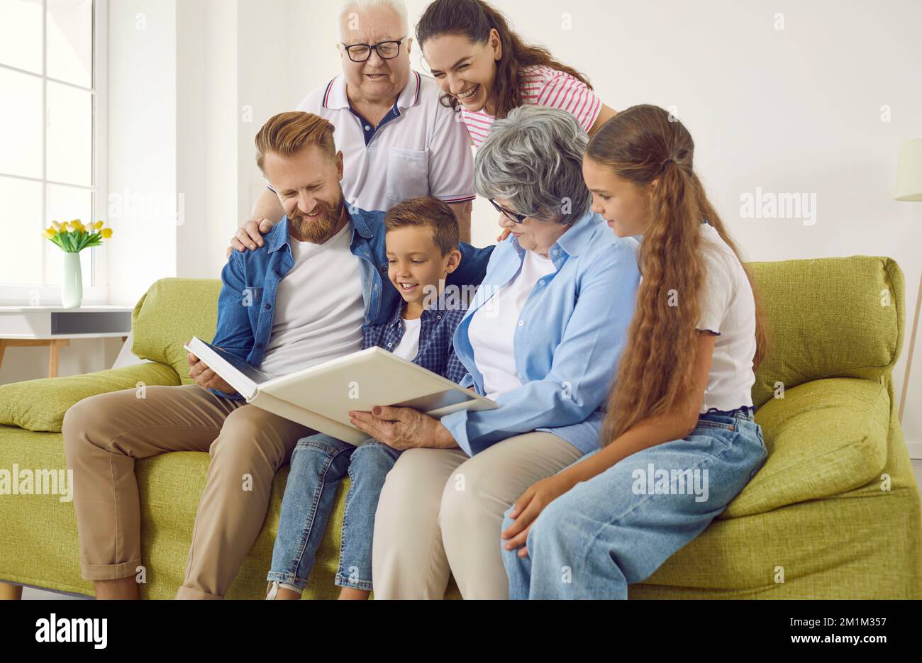 Happy family looking through their photo album while sitting on the couch at home Stock Photo