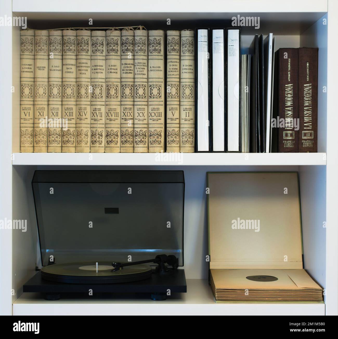 Modern record player spinning a recent vinyl record. Shown in a shelf together with a collection of old classical music records and modern vinyls. Stock Photo