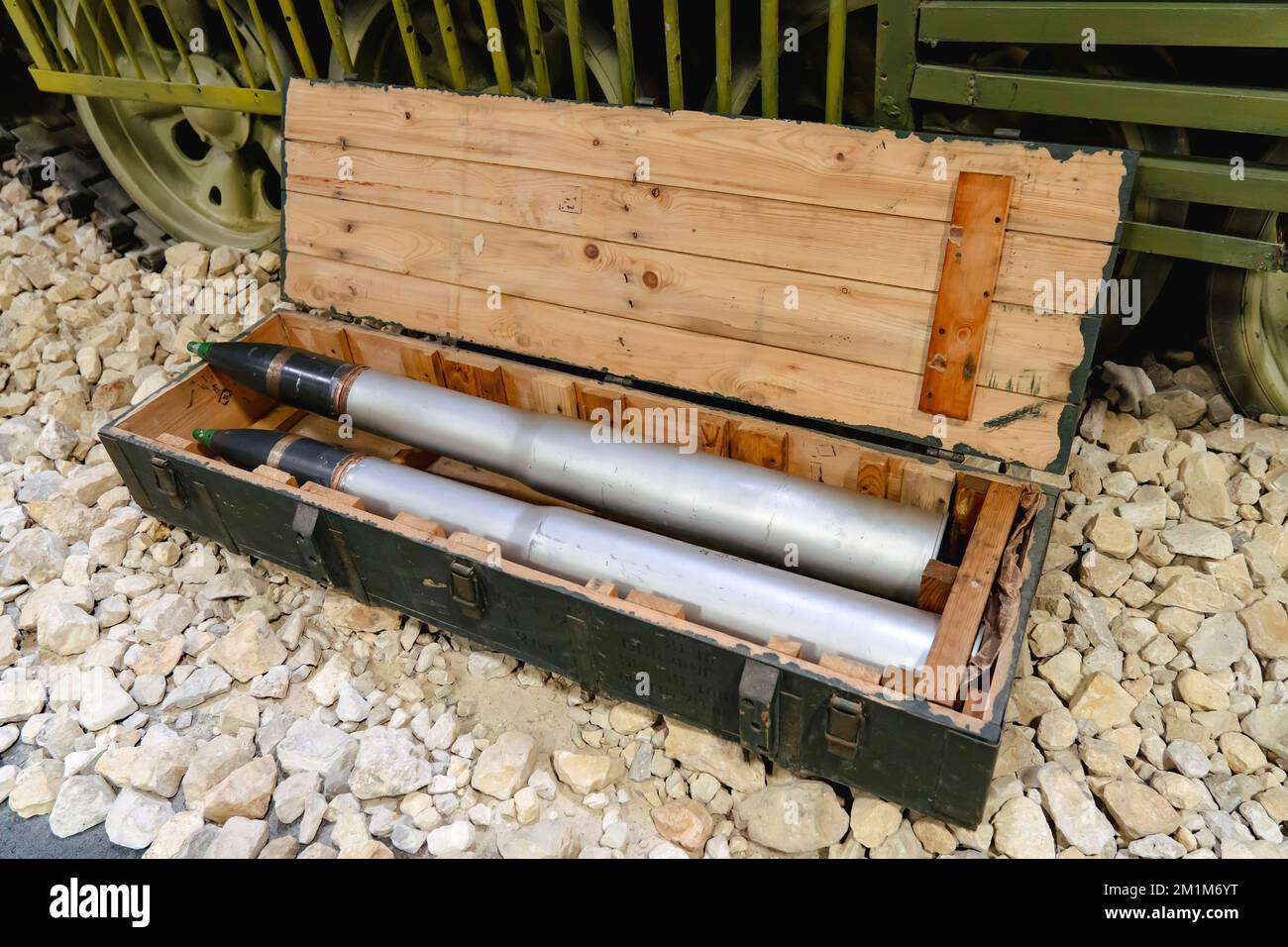 Shells for the tank in a green wooden box on the rocks near the tank. Supply of military ammunition. Stock Photo