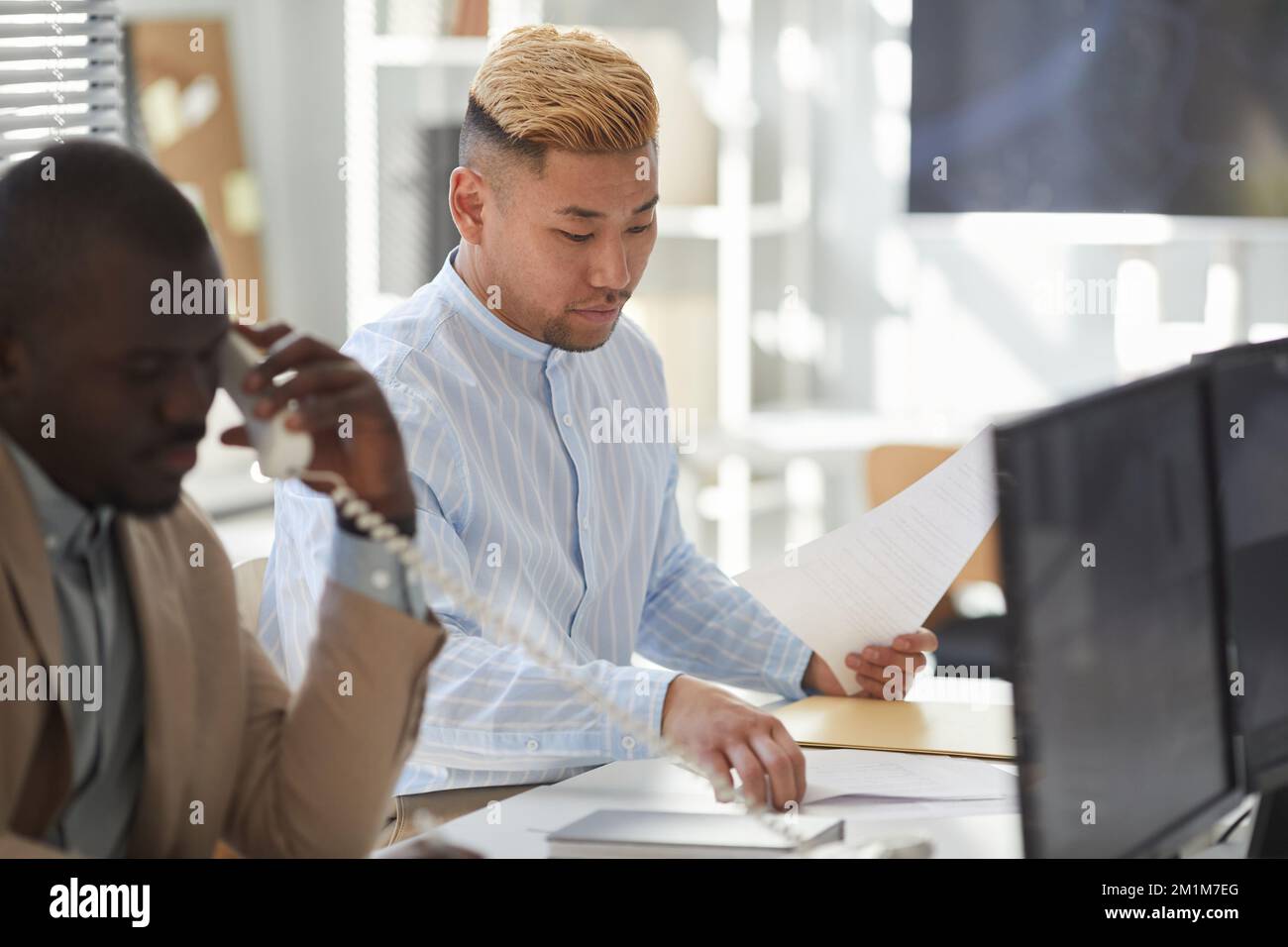 Portrait of young Asian man working with documents in surveillance center Stock Photo