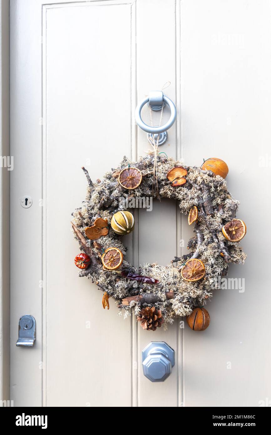 a wreath of fir branches adorned with red hypericum berries and pine cones decorate the white door before Christmas Stock Photo