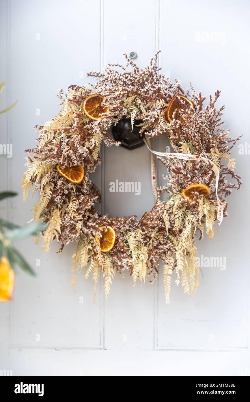 a wreath of fir branches adorned with red hypericum berries and pine cones decorate the white door before Christmas Stock Photo