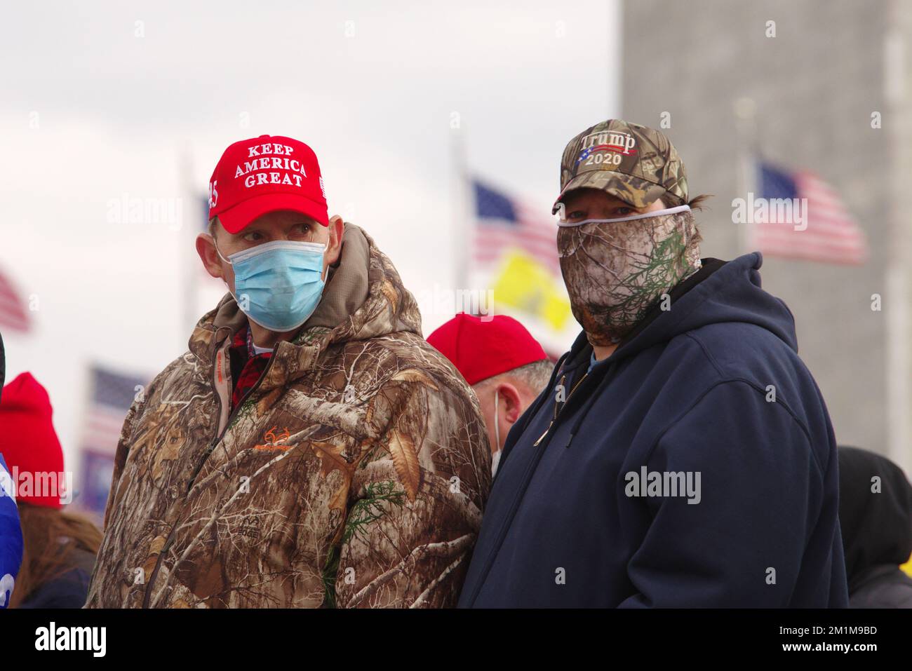 A pair of masked 'Stop the Steal' rally participants watches then-U.S. President Donald Trump's speech on January 6, 2021. Stock Photo