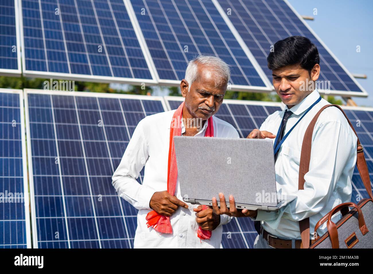 Bank officer explaning working solar power system on laptop to senior man at farmland - concept of expertise support and investment and sustainable Stock Photo