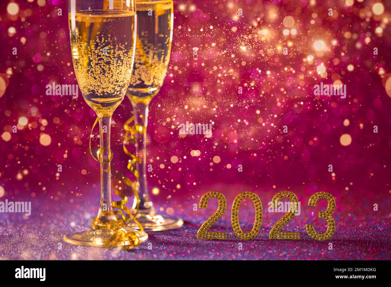 Happy New Year 2023..Christmas and New Year festive color bordeaux background with two cups, a glass of champagne and golden numbers on a background Stock Photo