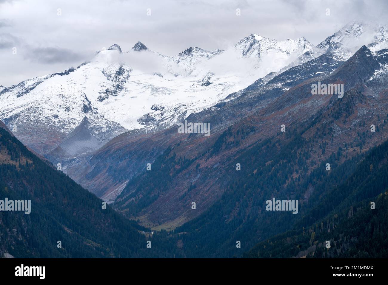 Gabler, Reichenspitze and Hahnenkamm peaks covered in snow and ice on a cloudy, rainy day of autumn. Majestic alpine peaks in the mist above Gerlos Stock Photo