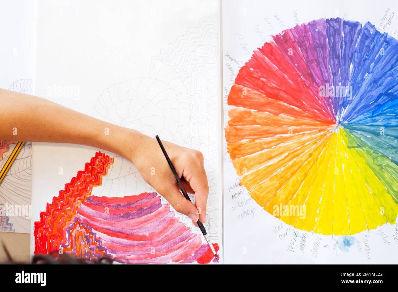 Hand and arm of school child painting colours with a painted colour wheel in the picture Stock Photo
