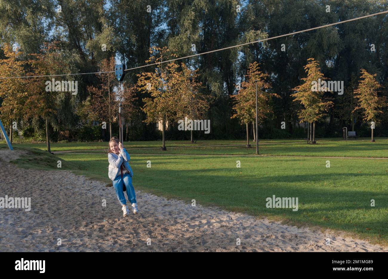 Autumn outdoor fun. Young girl riding a hanging bungee on the playground Stock Photo