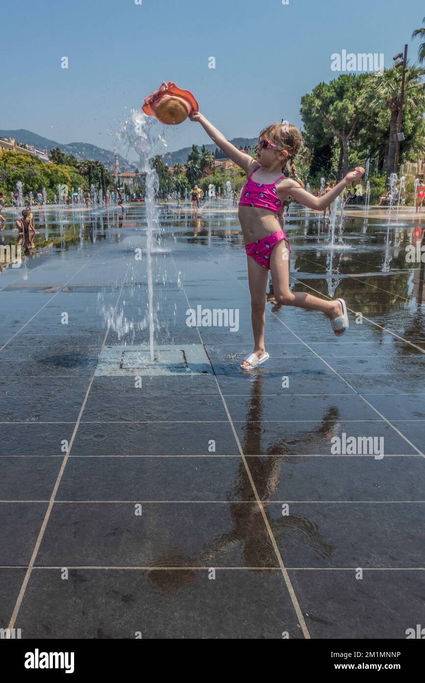 Child playing while cooling down at the water fountains in Promenade du Paillon in Nice, Cote D Azur, France. Stock Photo