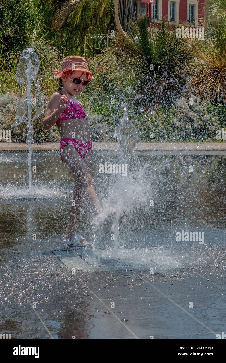 Child playing while cooling down at the water fountains in Promenade du Paillon in Nice, Cote D Azur, France. Stock Photo