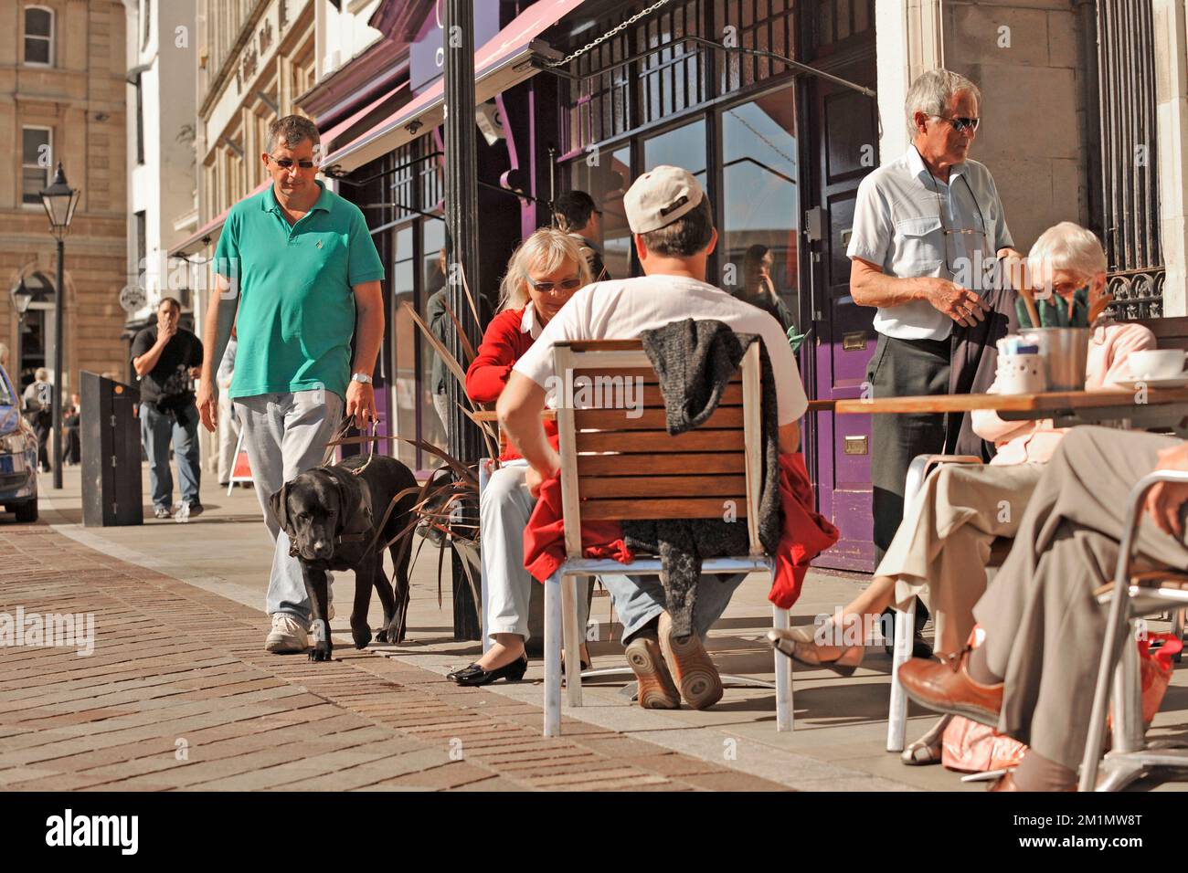 guide dog and trainer on busy pavement with obstacles Stock Photo