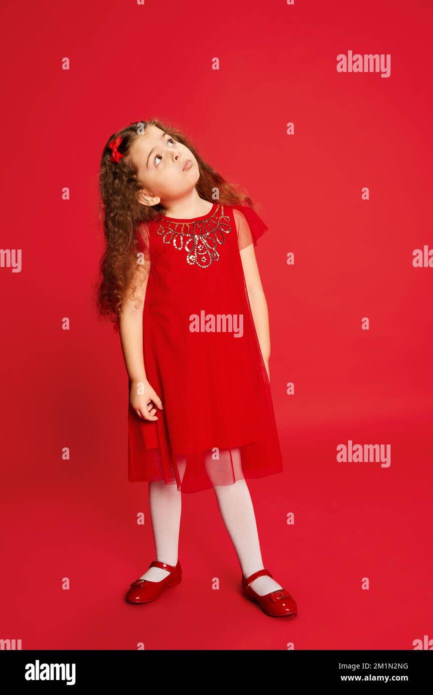Beautiful cute kid, little girl with long curly hair wearing red dress