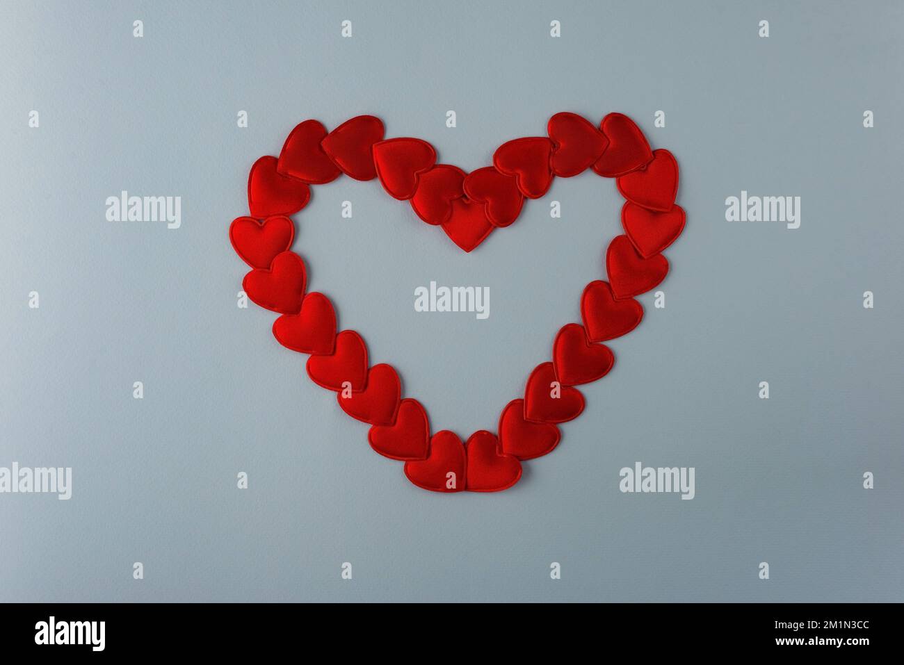 heart laid out from small red hearts on a blue background. Stock Photo