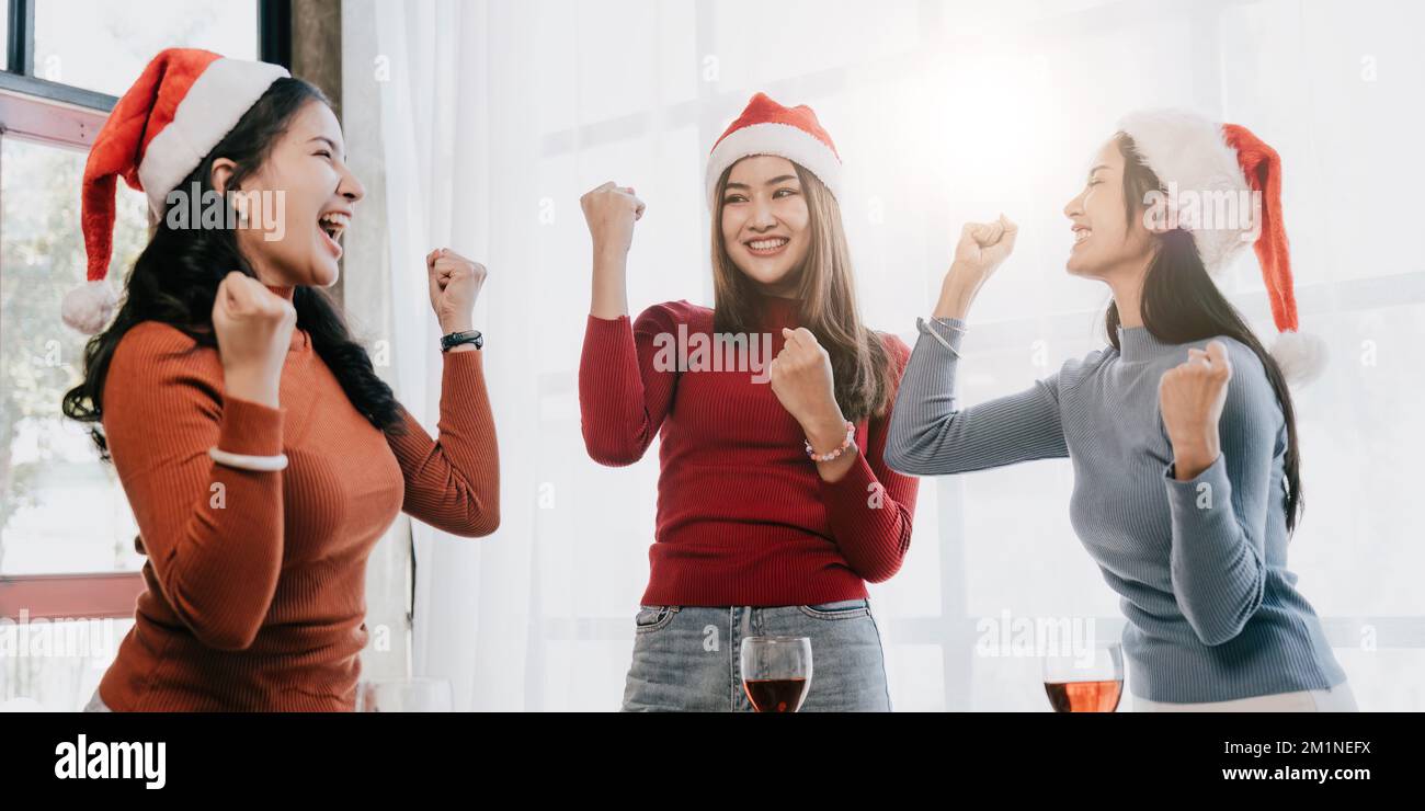 Group of Asian friends gather to celebrate Christmas with champagne and eating pizza at home. Joy of holiday party with friends or colleague concept Stock Photo