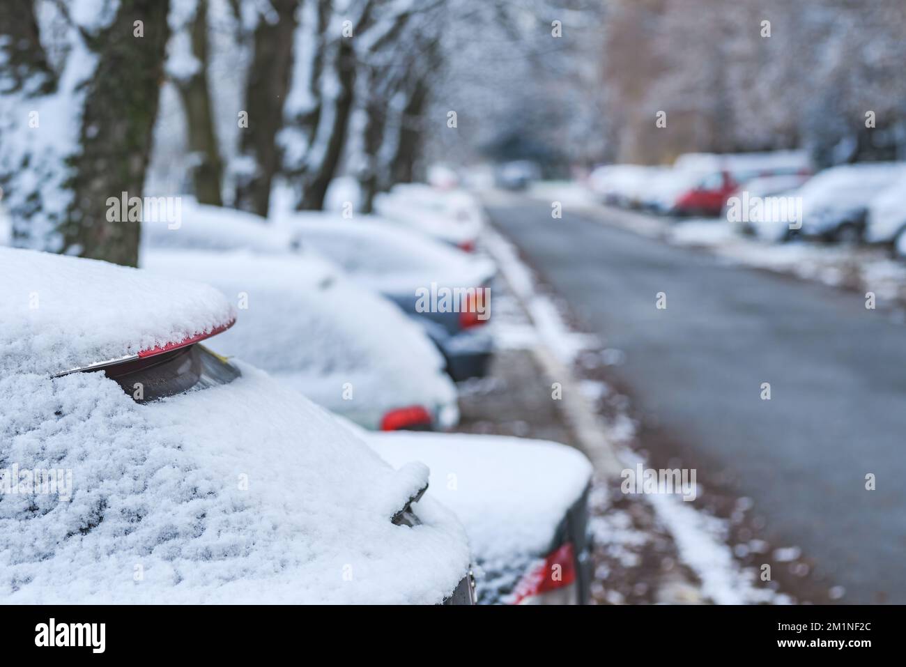 Cars under first snow of the winter on parking lot in residential ...