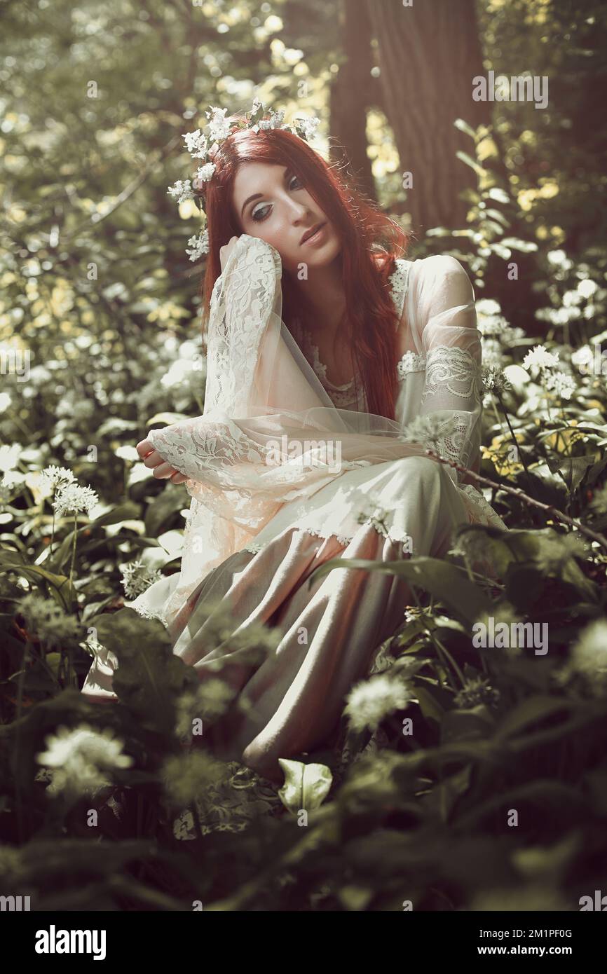 Beautiful red haired woman daydreaming in the woods Stock Photo