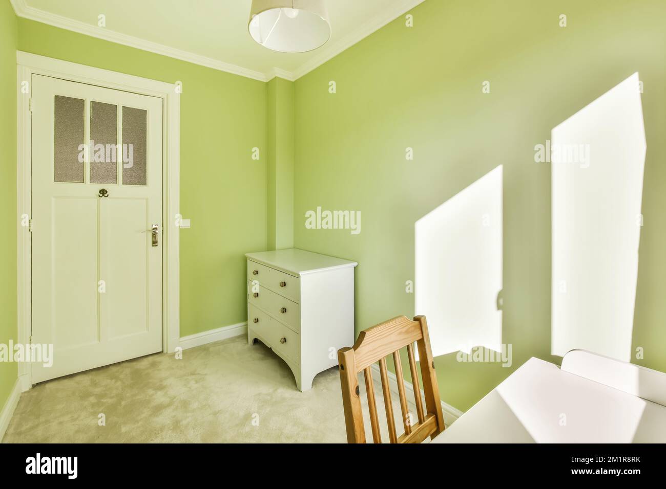 a room with green walls and white trim on the door, window, and chair in front of the room Stock ...