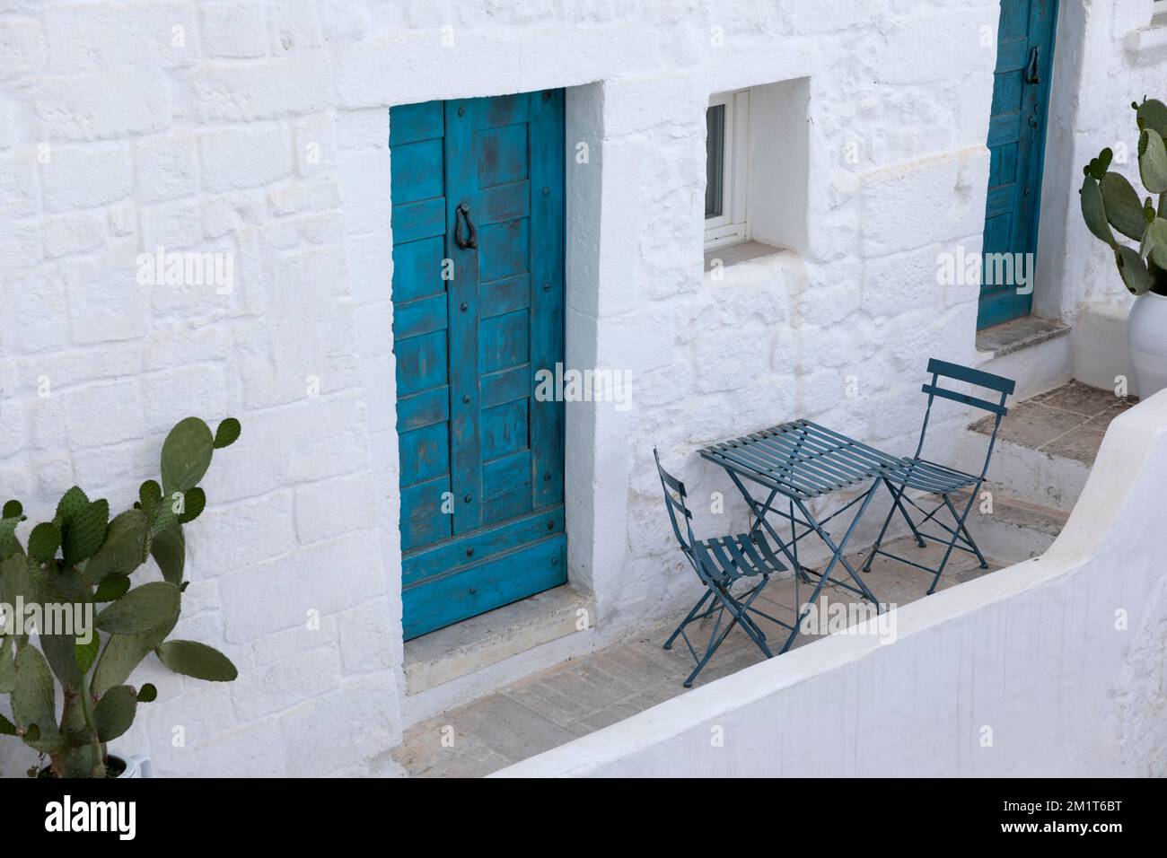 Whitewashed house with table and chairs on balcony and blue door, Ostuni, Brindisi province, Puglia, Italy, Europe Stock Photo