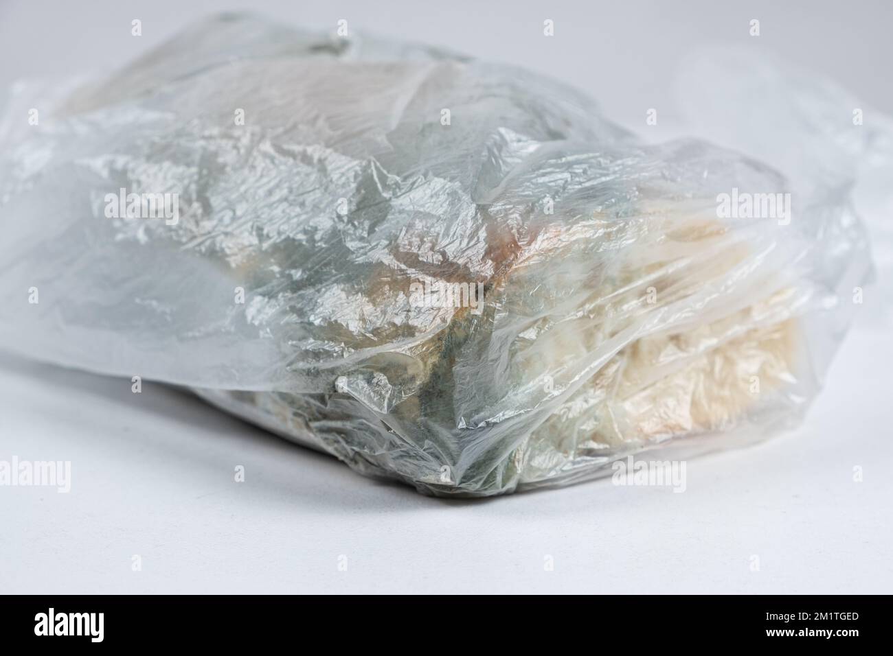 Bread with mold in a plastic bag on a white background, closeup Stock
