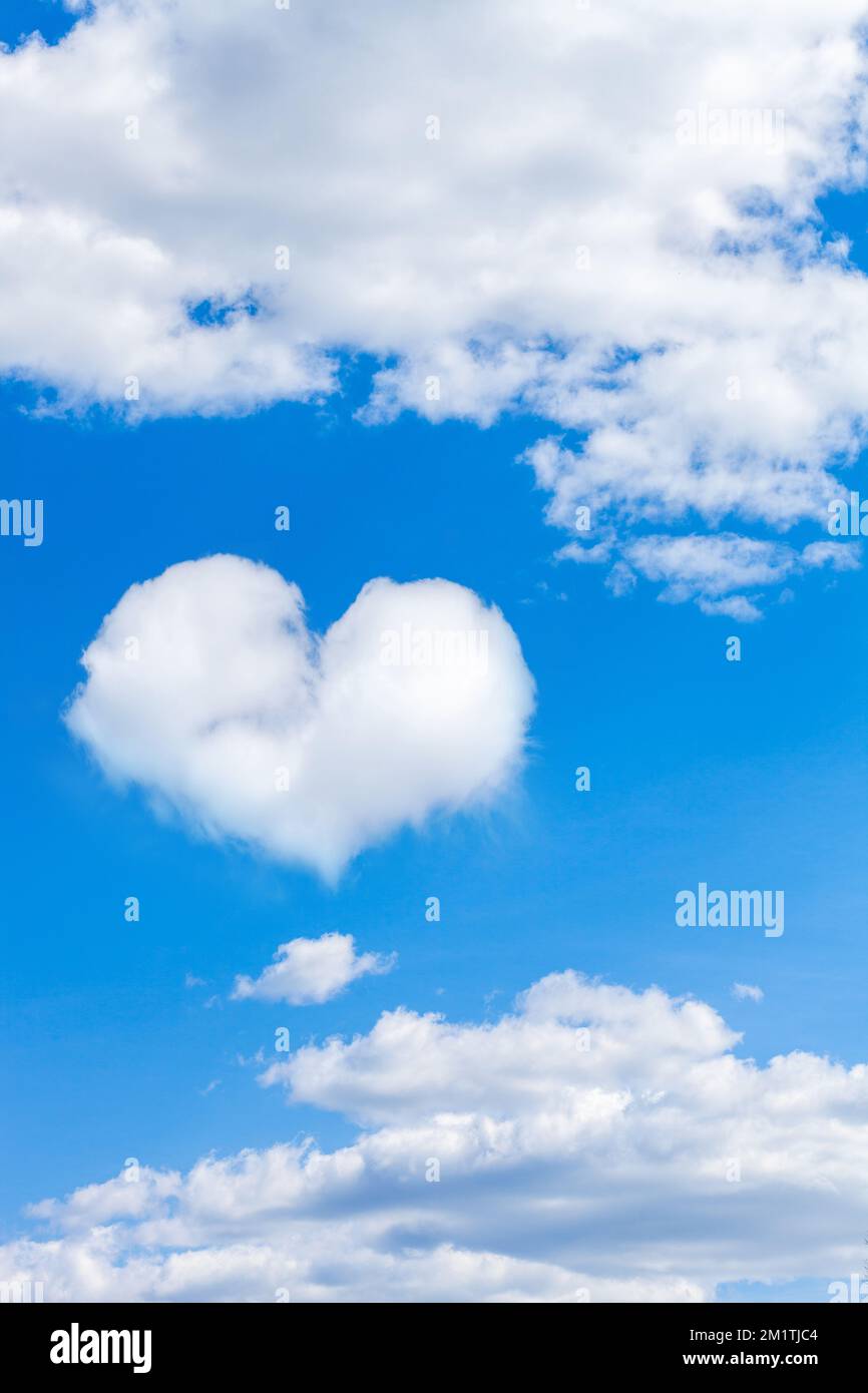 cumulus clouds on blue sky with heart shaped cloud. vertical frame ...