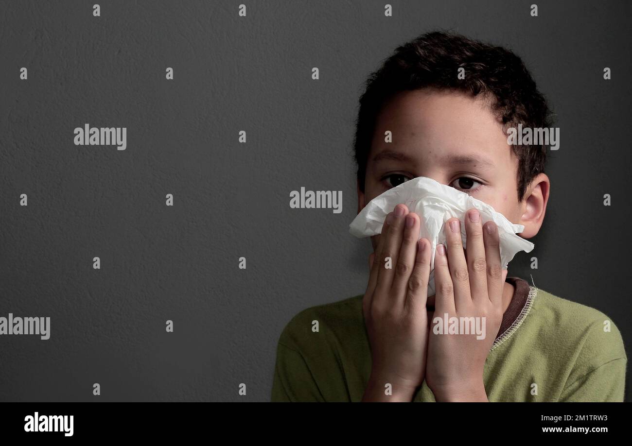 catching the flu child blowing nose after catching a cold with grey