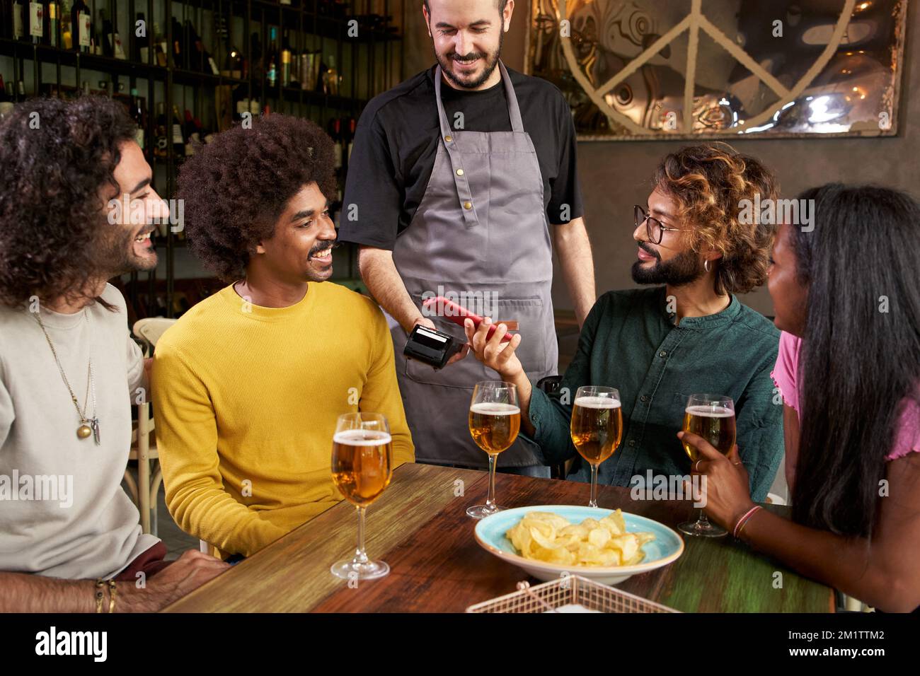 Customer making wireless or contactless payment using smartphone in a bar Stock Photo
